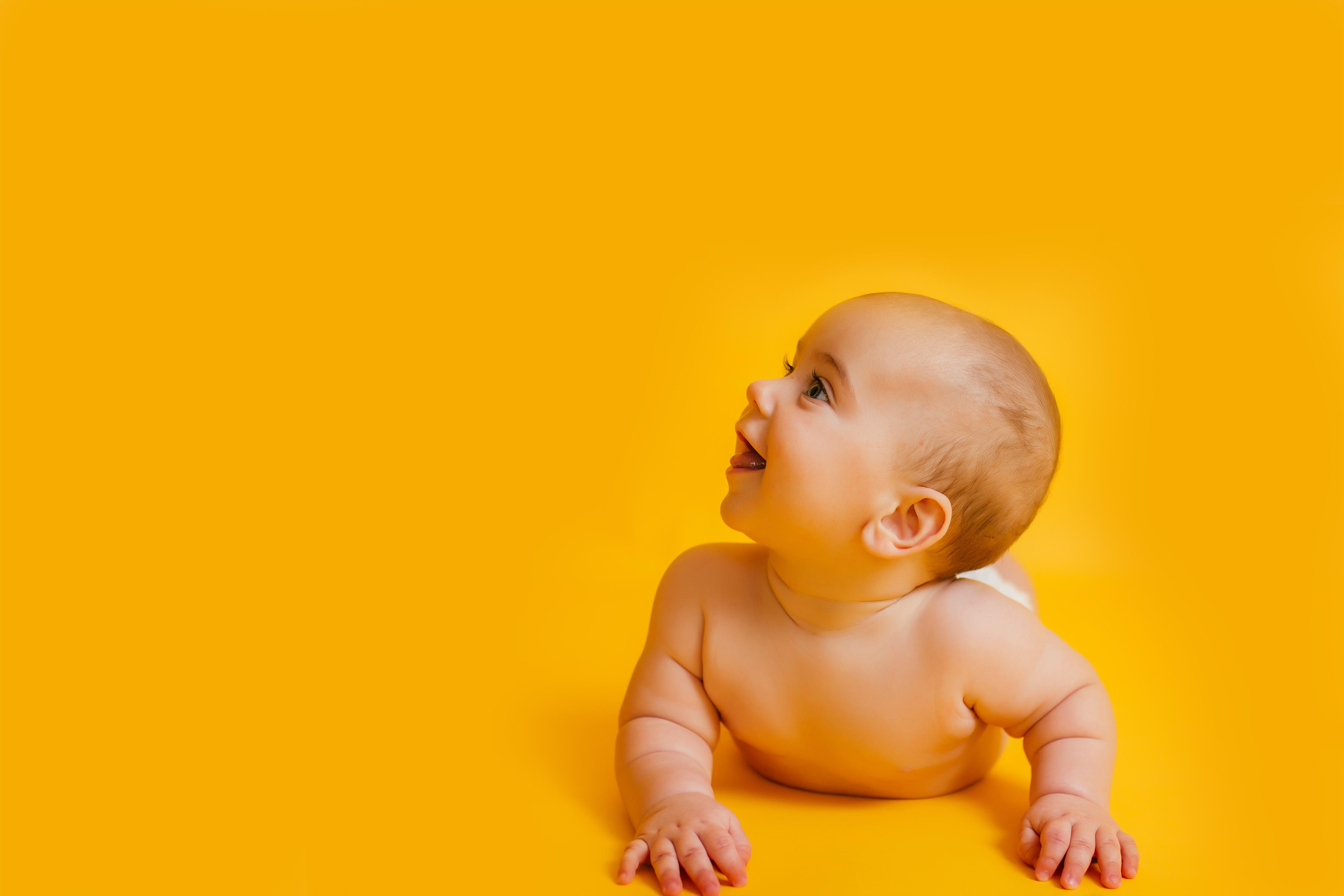 Bebê sorrindo sobre fundo amarelo